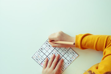 Teen girl solving sudoku at desk at school or at home. View from above