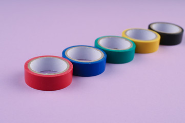 Several round rolls of colored plastic tape lie in a row