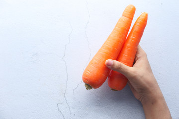 top view of women hand holding carrot on white background.