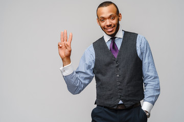 African-American businessmanman showing THREE by finger over grey background