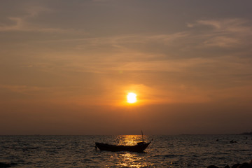 Silhouette of a fishing boat in the middle of the picture, in the evening there is a sunset at the sea
