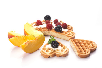 Waffles with berries and peaches isolated on white background