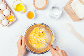 Mixes eggs in metal bowl next to ingredients for homemade bakery