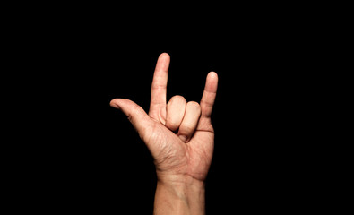 The man's hand holding his finger shows the symbol I love you on a black background.