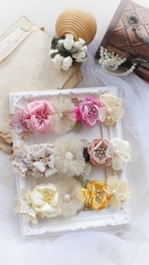 Headband flower with pastel color made out of flower fabric on a white photo frame. The handmade floral is great for hair accessories with its colorful flower and beautiful for hair band.