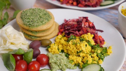 Healthy organic vegan breakfast featuring scrambled tofu, vegan pancakes, fresh vegetables and salad. 