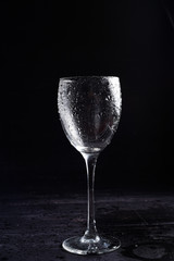 Wine glass in black and white on a black surrface with reflection and water drops