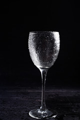 Wine glass in black and white on a black surrface with reflection and water drops