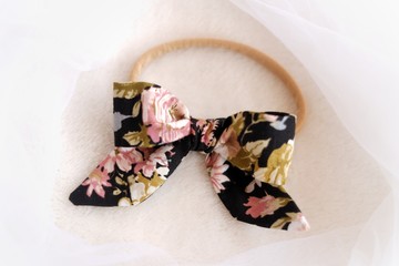 Obraz na płótnie Canvas A bow headband made out of cotton fabric with black color and flower patterns. This beautiful handmade craft bow is great as hair accessory for girls.