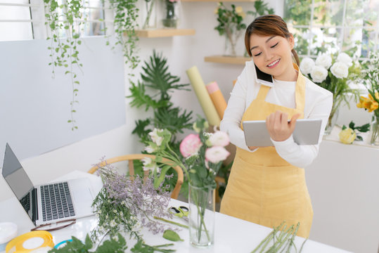 Asian florist with touchpad standing by workplace