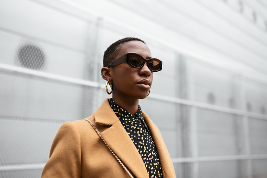 Confident black woman in sunglasses standing on street
