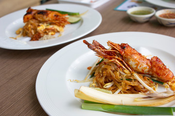 Fried noodles Pad Thai with prawn, piece of banana blossom and chive on white plate