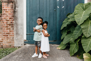 Two African American kids / brother and sister standing back to back.