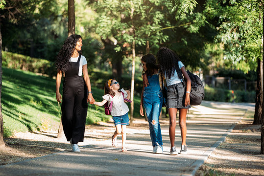 girlfriends and adult woman walking to school in a green park