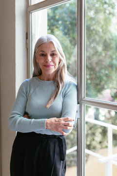 Confident Senior Lady Leaning On Office Window