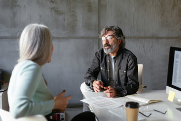 Mature colleagues discussing project in office