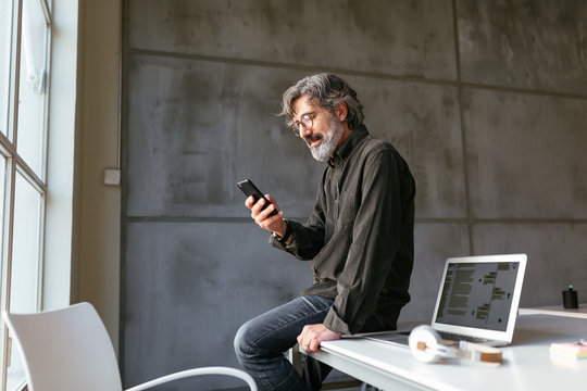 Senior employee using smartphone in office - Powered by Adobe