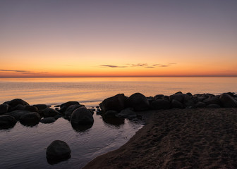 Fototapeta na wymiar orange sunset by the sea, black stone silhouettes against the sea background, summer