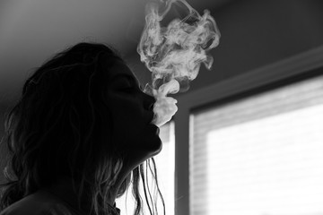 Black and white image of woman smoking indoors.