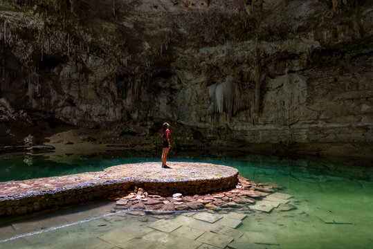 Woman standing in the middle of a lake in a cave