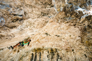 Climber clipping carabiner in the rooftop of a cave