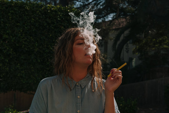 Female smoking electronic cigarette outdoors.