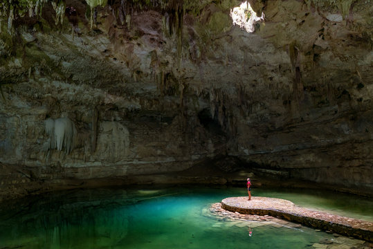 Woman standing in the middle of a lake in a cave