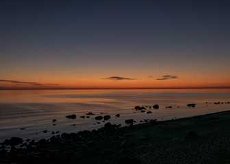 Naklejka premium orange sunset by the sea, black stone silhouettes against the sea background, summer