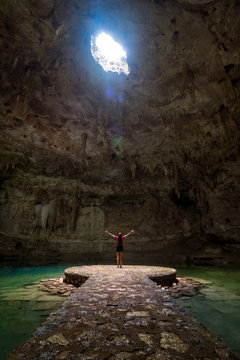 Woman standing in the middle of a lake in a cave