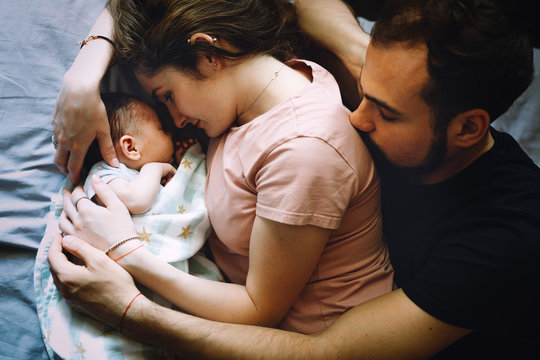 Mother and father with a newborn daughter on a bed