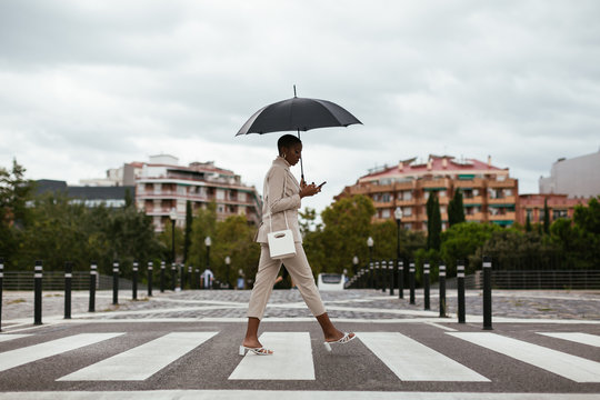 Black lady with umbrella crossing road