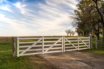 White wooden gate in the field, open and closed