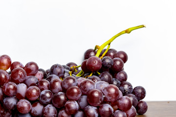 Close-up of red seedless grapes with water droplets on a white background