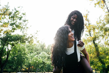 smiling mum riding daughter on a green park