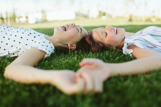 Two teenage girls lying on the grass laughing