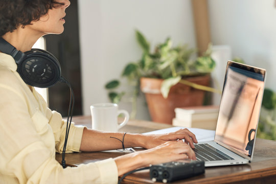 Crop woman editing podcast on laptop