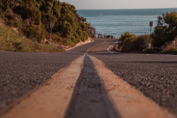An empty road leading toward the beach and ocean on a sunny afternoon.