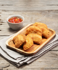 Typical Colombian empanadas with spicy sauce on wooden surface
