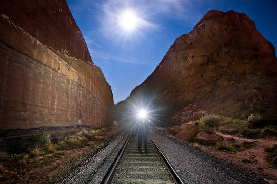 Person lighting up canyon with a headlamp on train tracks, Moab Utah
