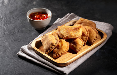 Typical Colombian empanadas usually served with spicy sauce on black background