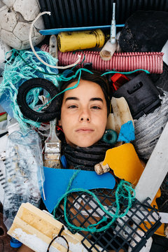 Conceptual portrait of a young girl surrounded by plastic waste from oceans