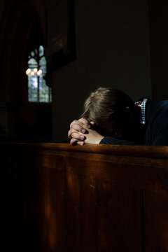 Man bows his head in prayer in Church.