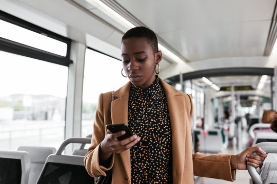 Black lady using smartphone in modern vehicle