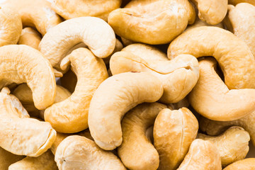 fresh cashew nuts on a white dish above the white background