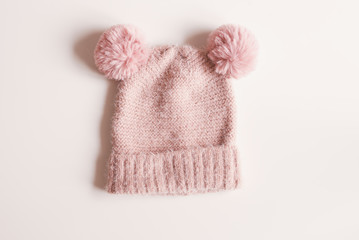 Knitted woolen hat of pink color with pompoms on white background. Autumn or winter warm clothing