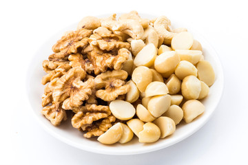 Variety of fresh nuts on a white dish above the white background