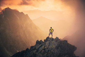 Man on the top of the hill watching wonderful scenery in mountains during summer colorful sunset in...