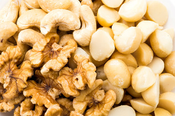 Variety of fresh nuts on a white dish above the white background