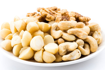 Some cashews, macadamias, and walnuts on a white dish.