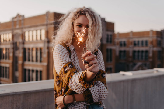 A young blonde woman in her twenties on a rooftop at sunset